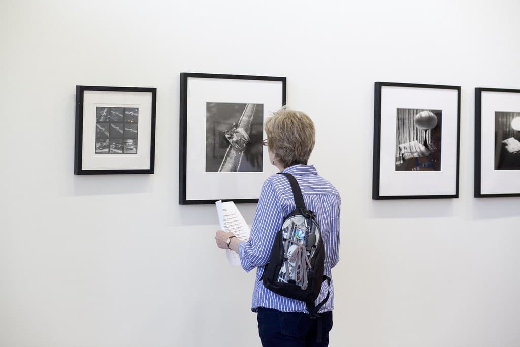 A visitor viewing framed photographs at a gallery opening