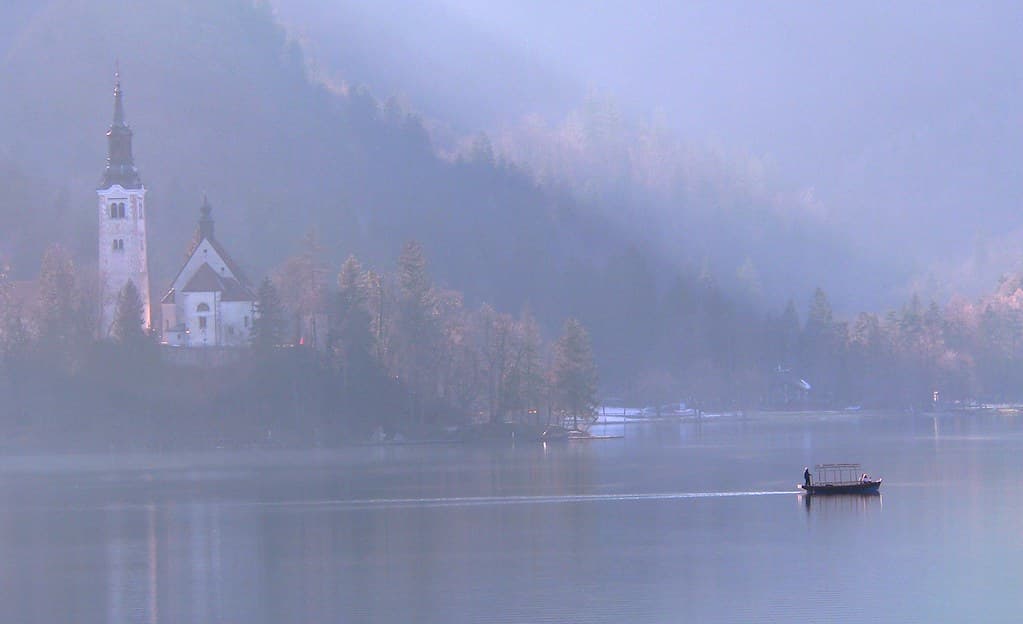 A calm urban lake ringed by trees reflecting the sky